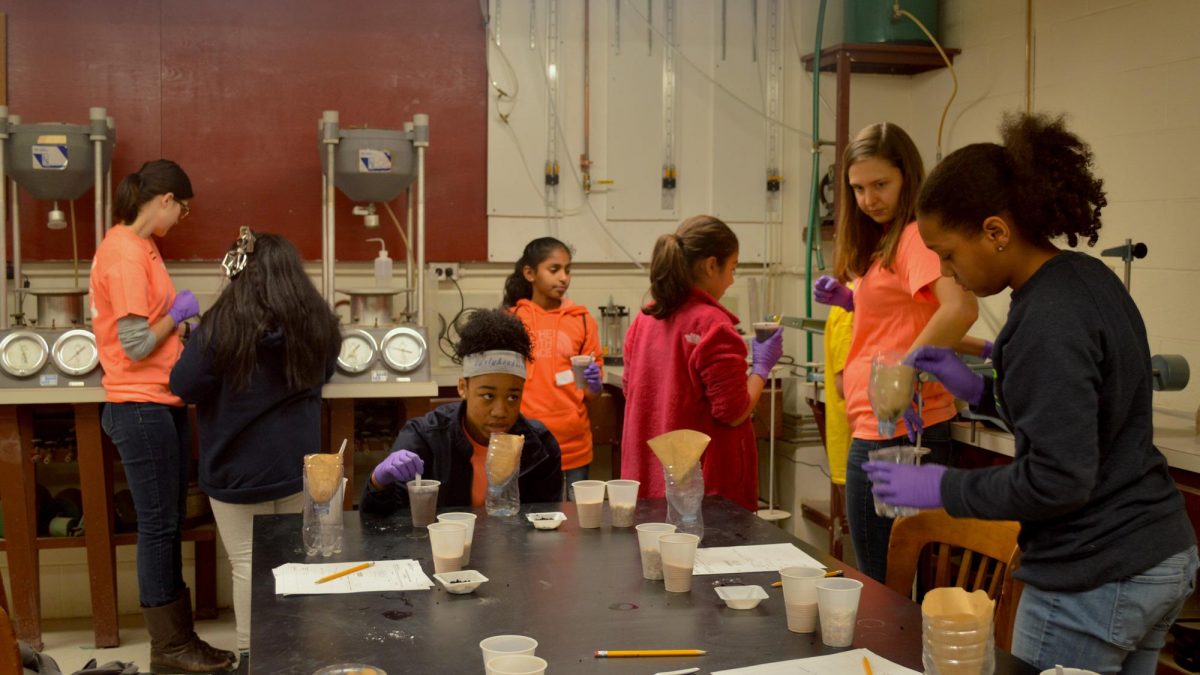 Volunteers working with students to test water in a lab